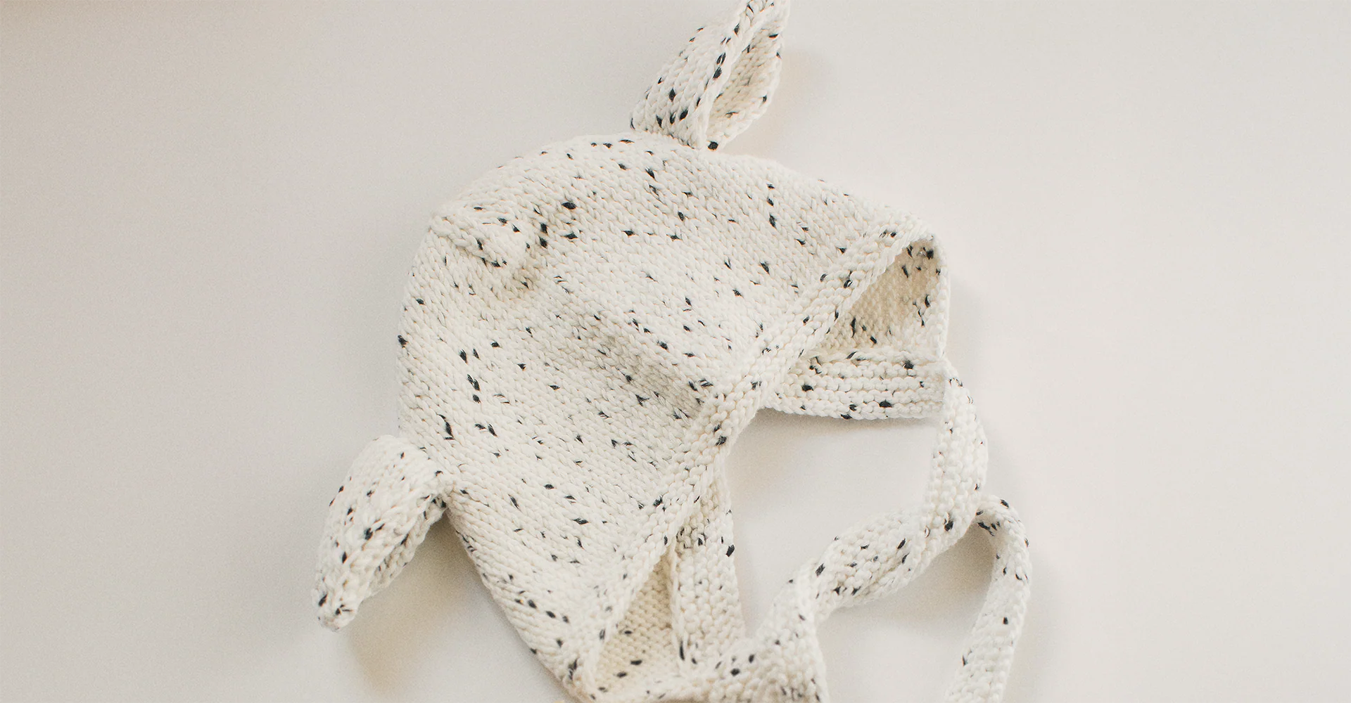 Hand-knitted speckled baby bonnet made from soft Pima cotton