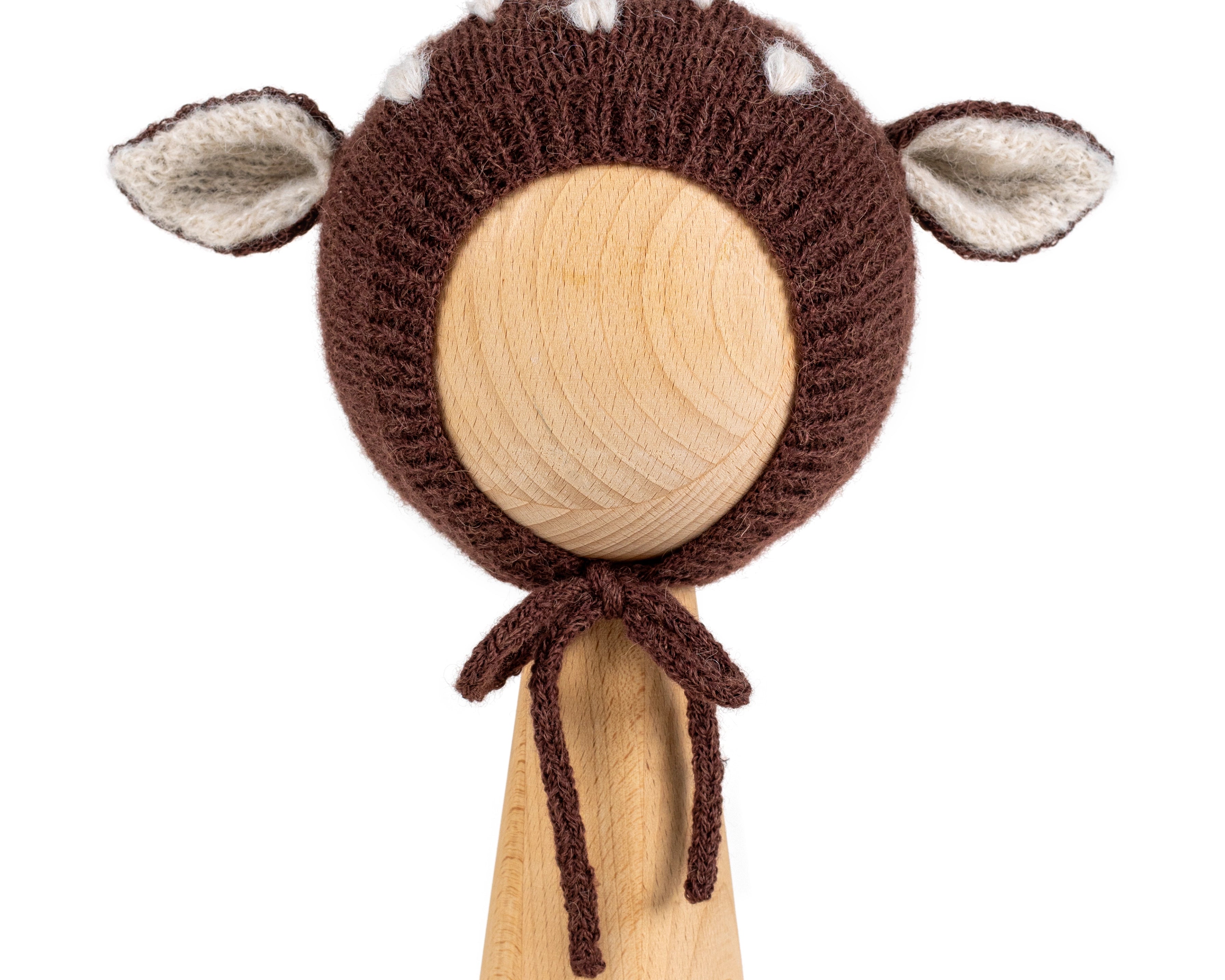 Brown knitted baby bonnet with deer ears and white spots in Hot Chocolate, shown on a wooden display head.