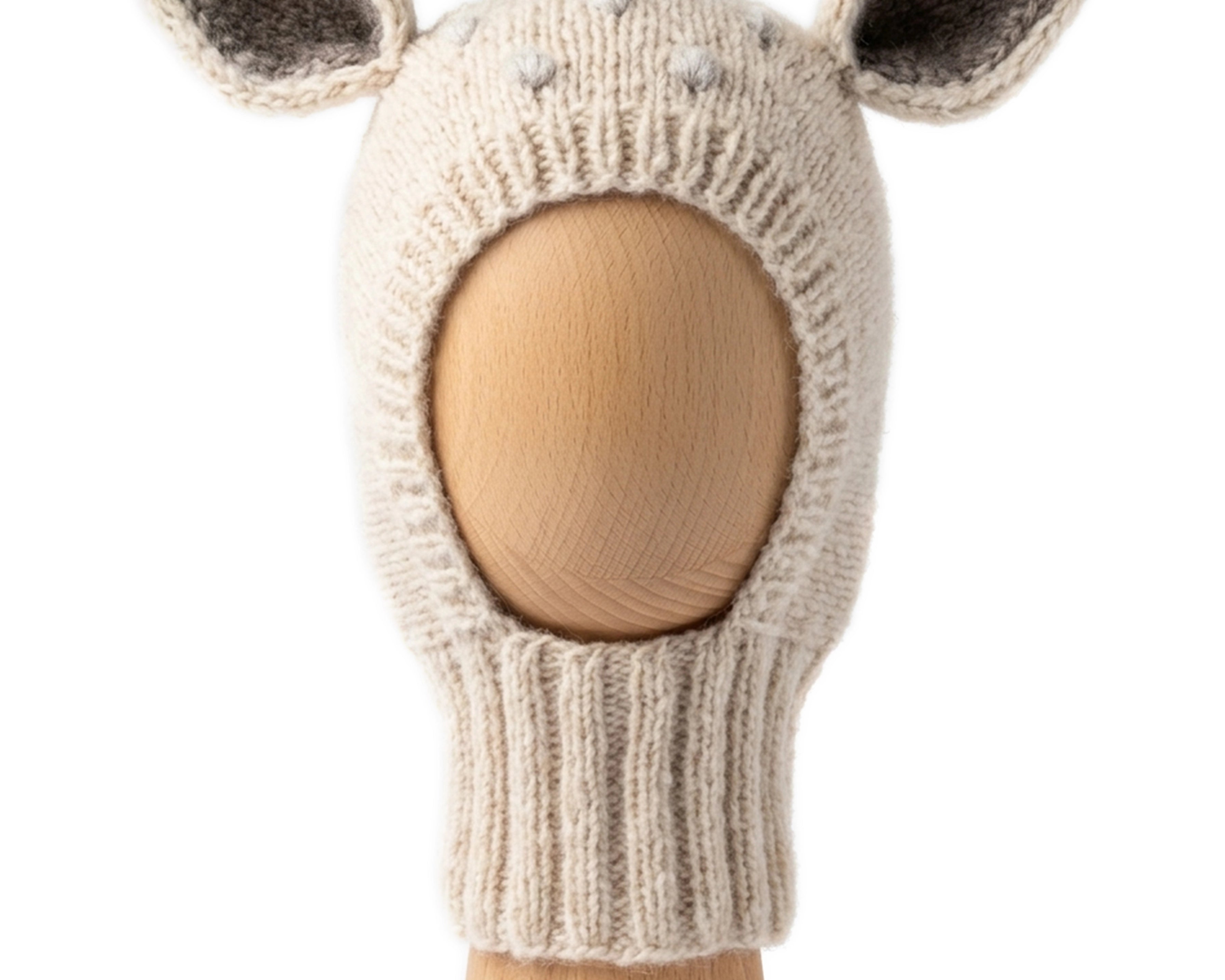 Bambi Balaclava, a knitted balaclava for kids with ears, shown in wheat with pearl grey spots on a wooden display head.