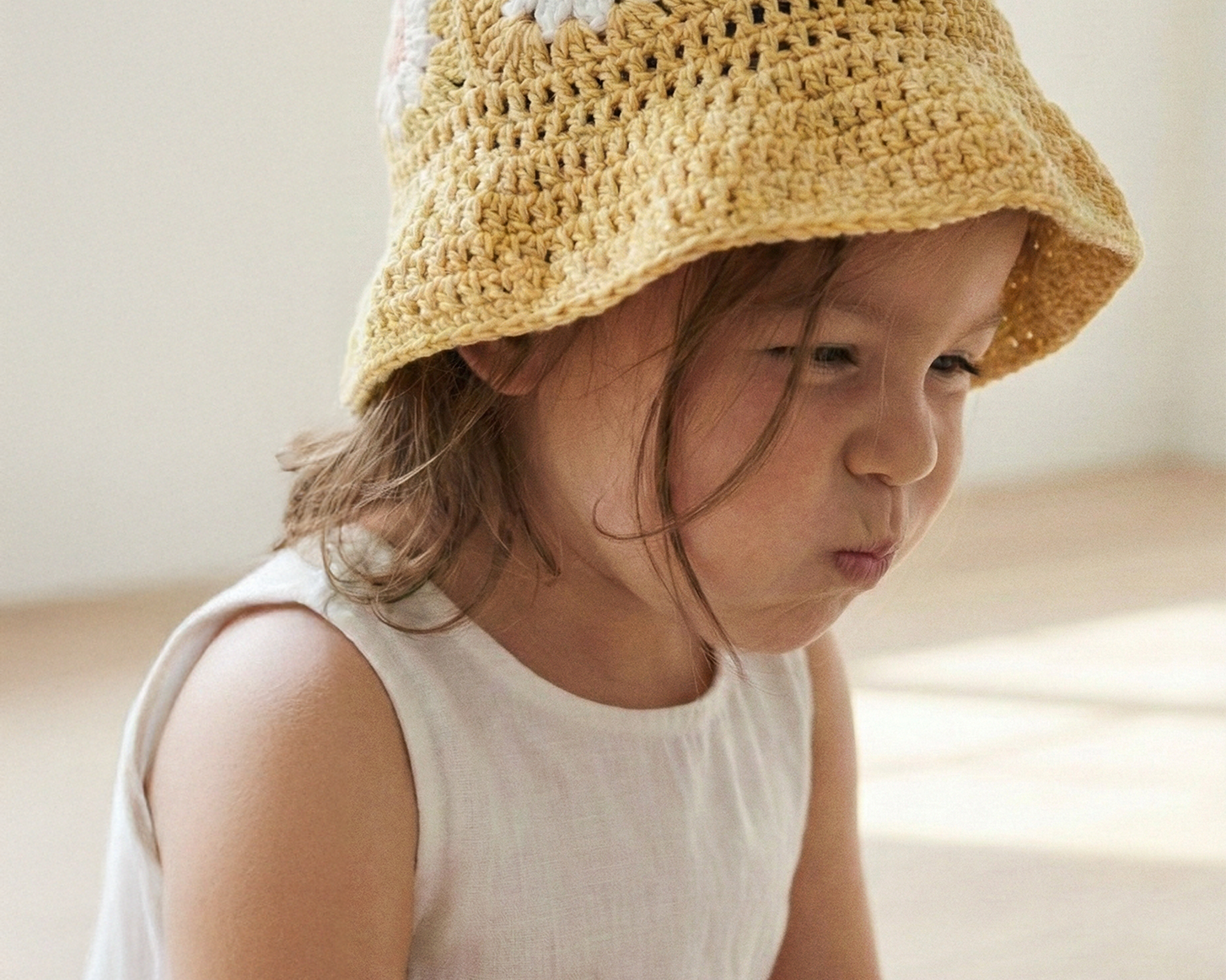 Dziewczynka w żółtym szydełkowym kapeluszu Daisy Buttercup Yellow w białej sukience | Girl wearing yellow Daisy crocheted toddler sun hat in white dress