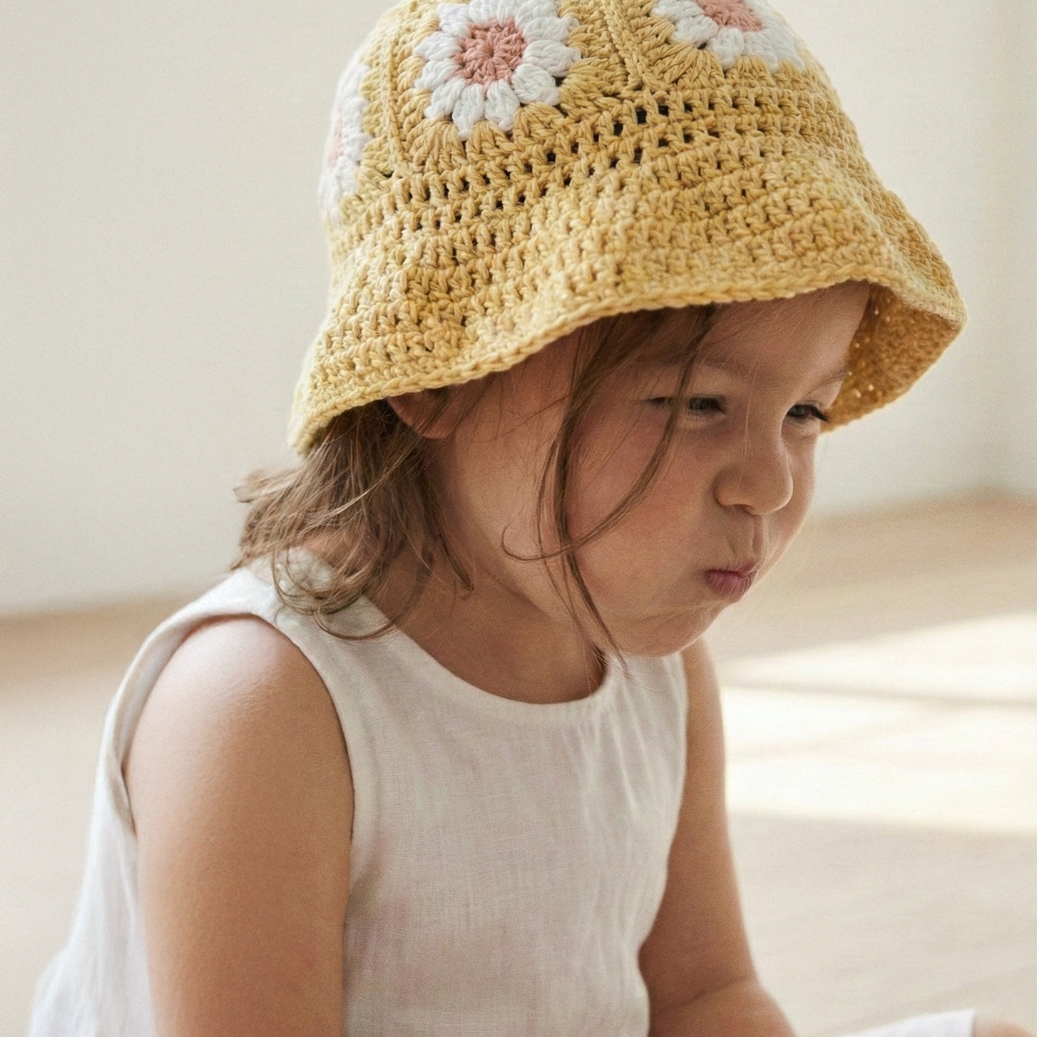 Dziewczynka w żółtym szydełkowym kapeluszu Daisy Buttercup Yellow w białej sukience | Girl wearing yellow Daisy crocheted toddler sun hat in white dress