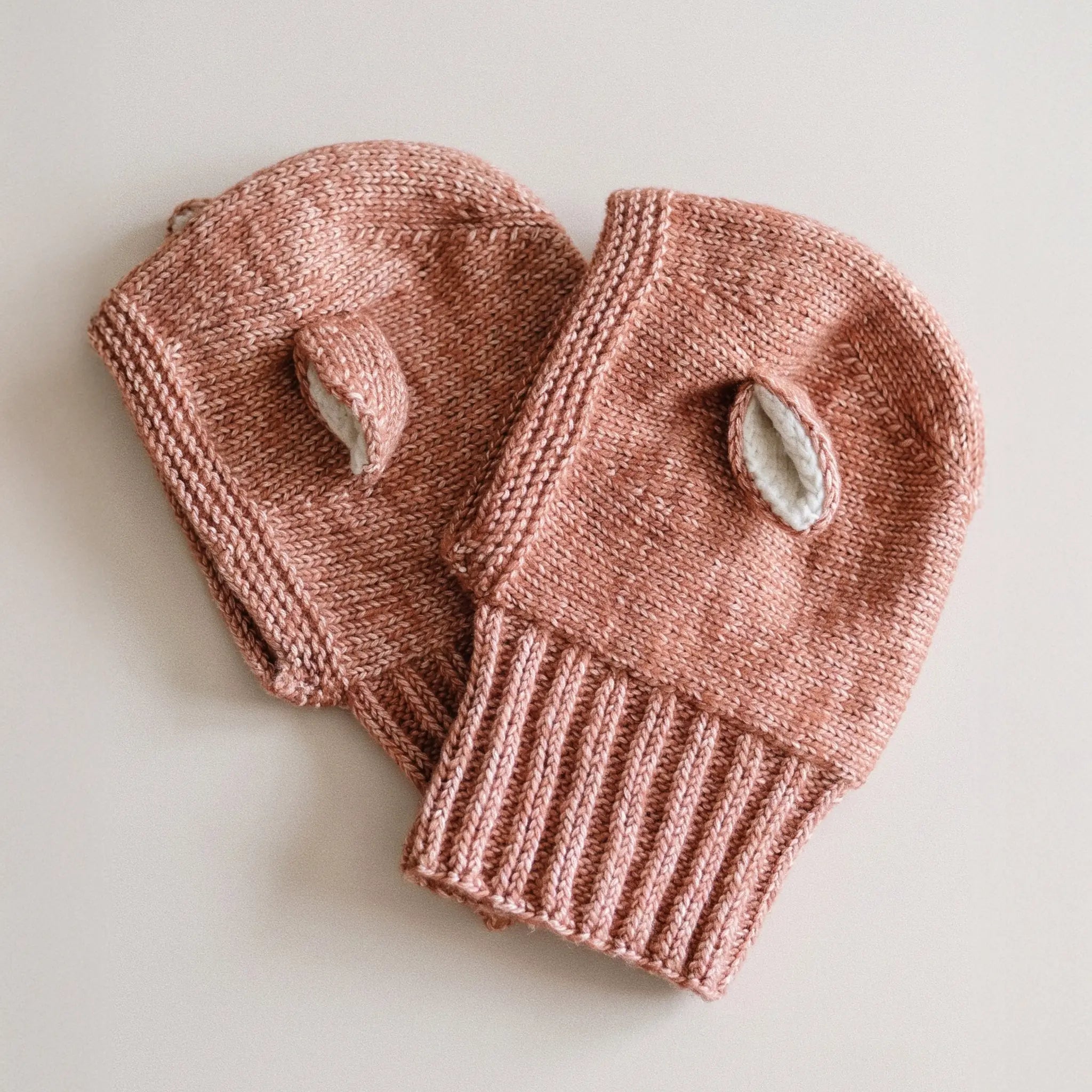Two Fairy Balaclavas in Terracotta laid flat, showing the ribbed neck and the cream-lined ears.