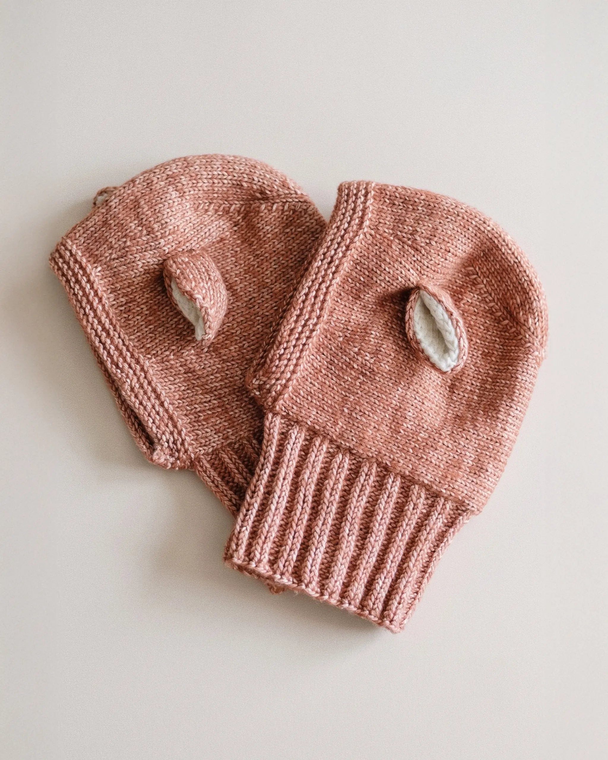 Two Fairy Balaclavas in Terracotta laid flat, showing the ribbed neck and the cream-lined ears.