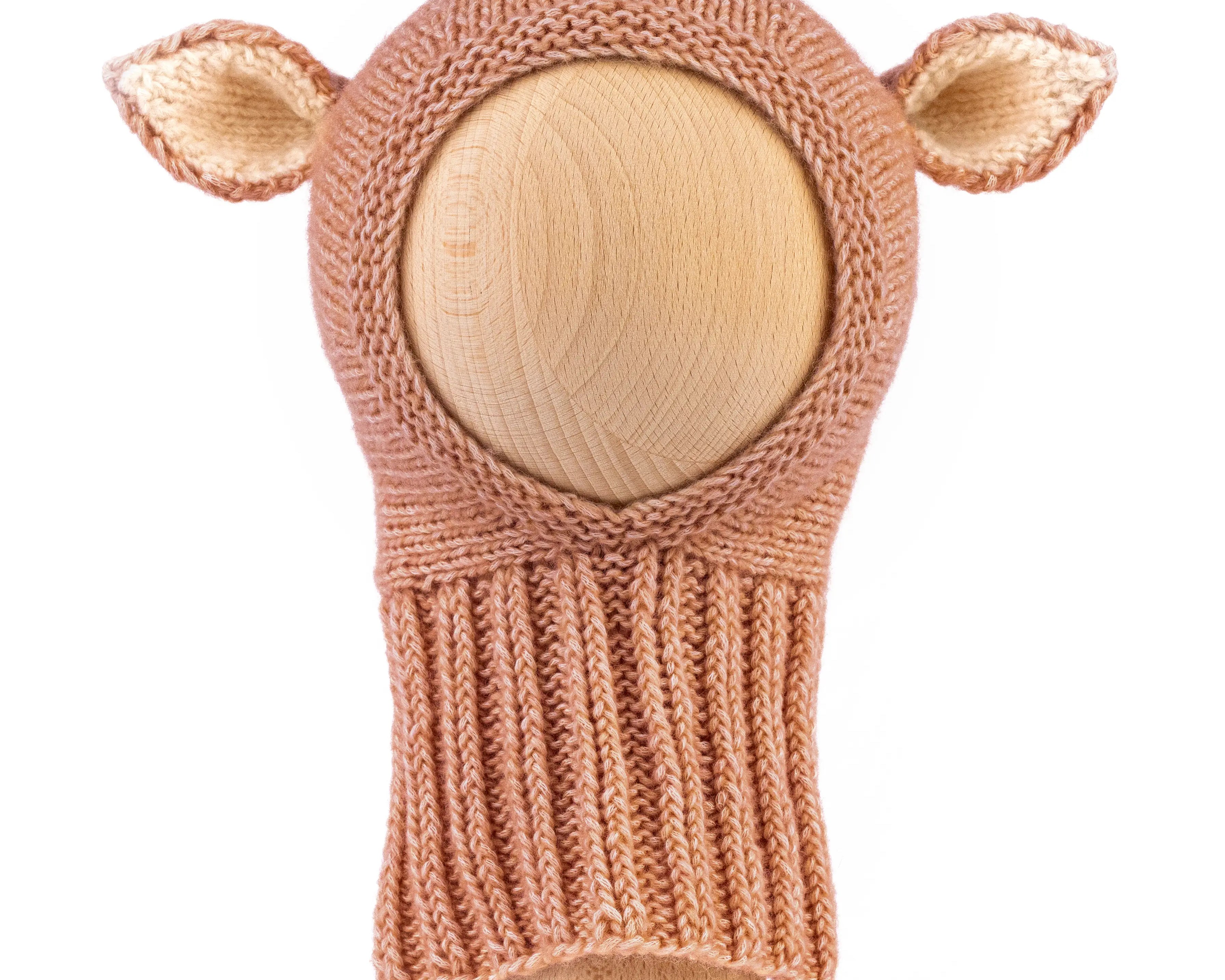 A hand-knit baby hat in a warm tan color, featuring two small pointed ears on the sides, displayed on a light wood mannequin head against a white background.