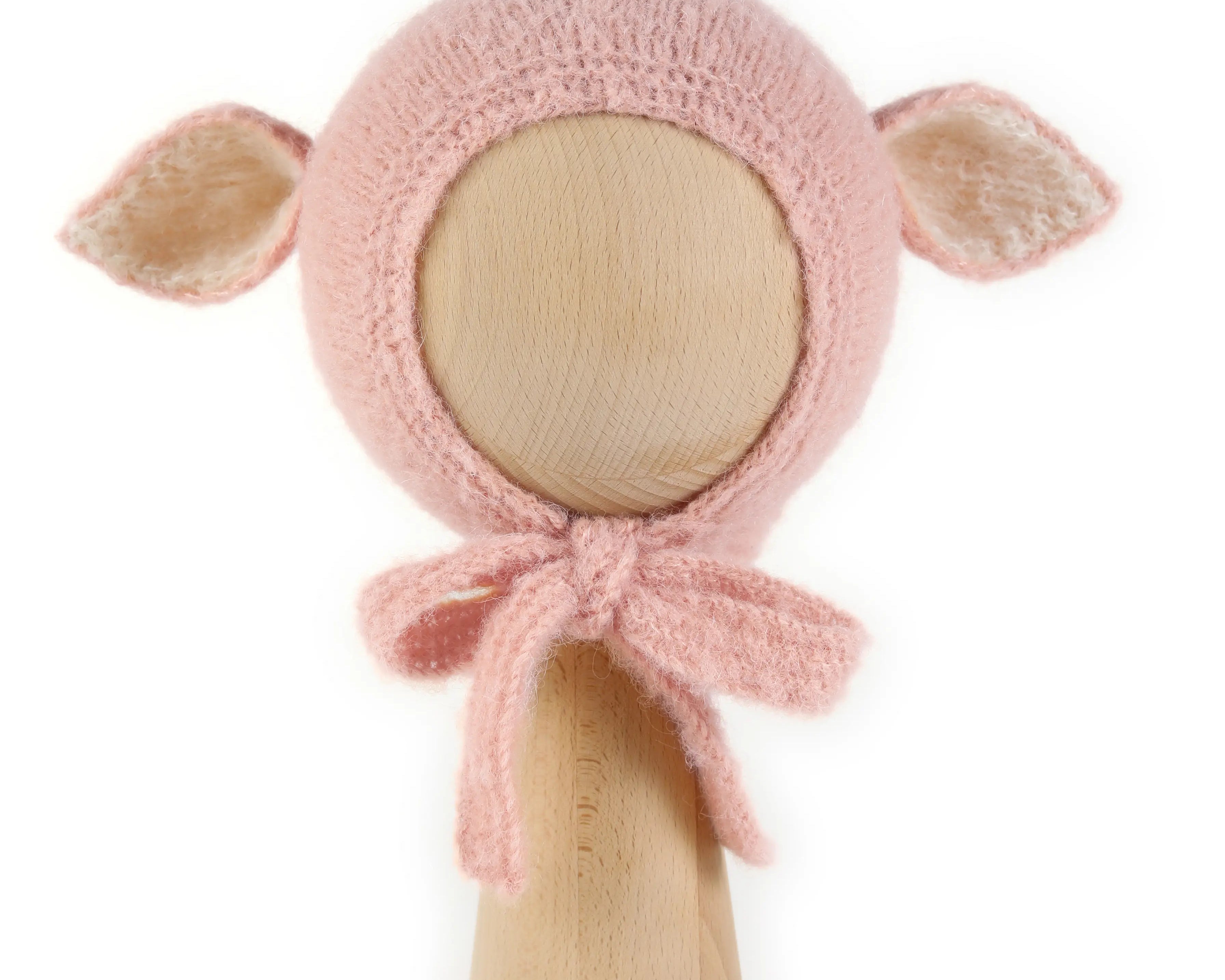 Fairy Hat in Baby Pink, a knitted bonnet with ears in alpaca and silk, with creme ear linings and ties tied under the chin, shown on a wooden display head.