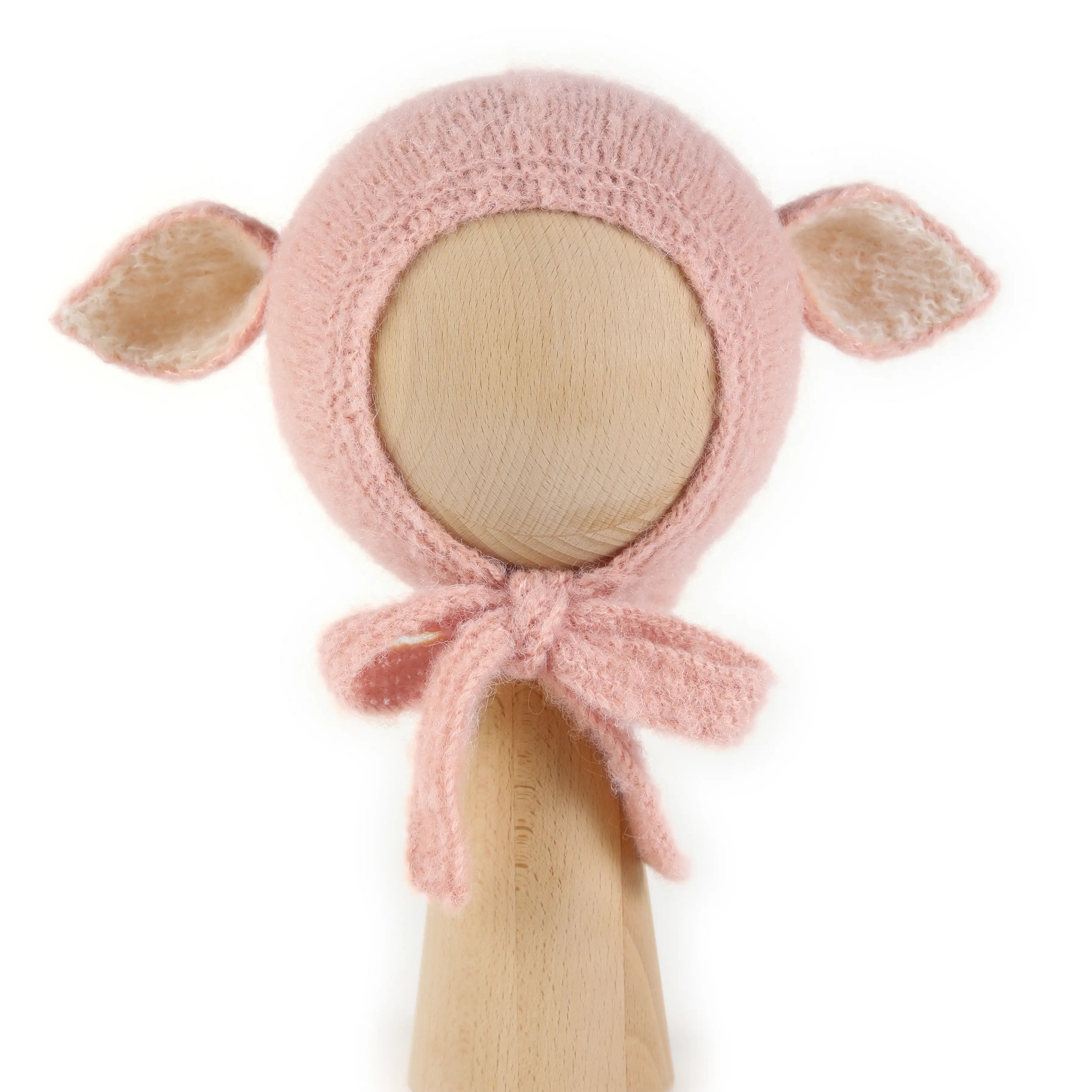 Fairy Hat in Baby Pink, a knitted bonnet with ears in alpaca and silk, with creme ear linings and ties tied under the chin, shown on a wooden display head.