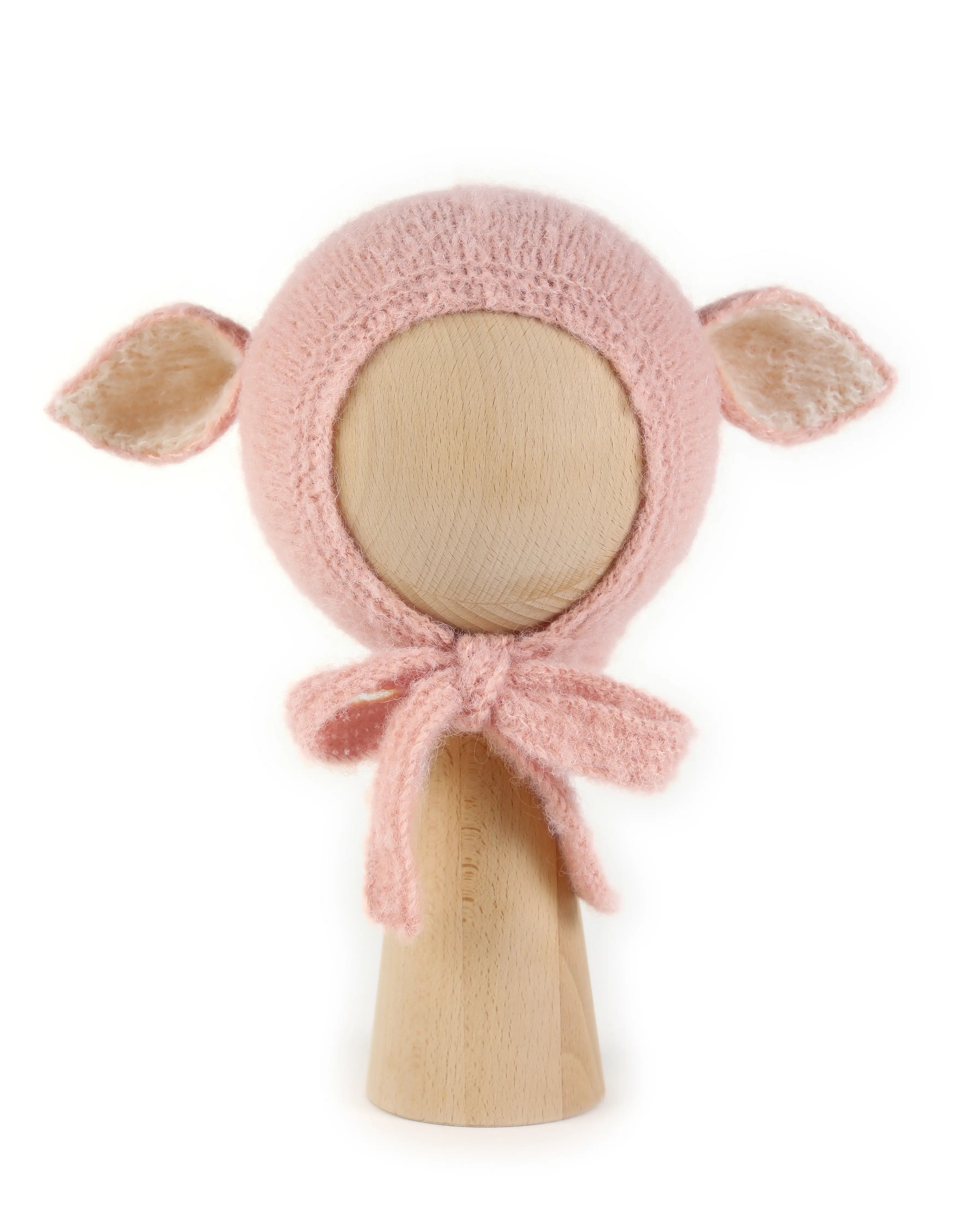 Fairy Hat in Baby Pink, a knitted bonnet with ears in alpaca and silk, with creme ear linings and ties tied under the chin, shown on a wooden display head.