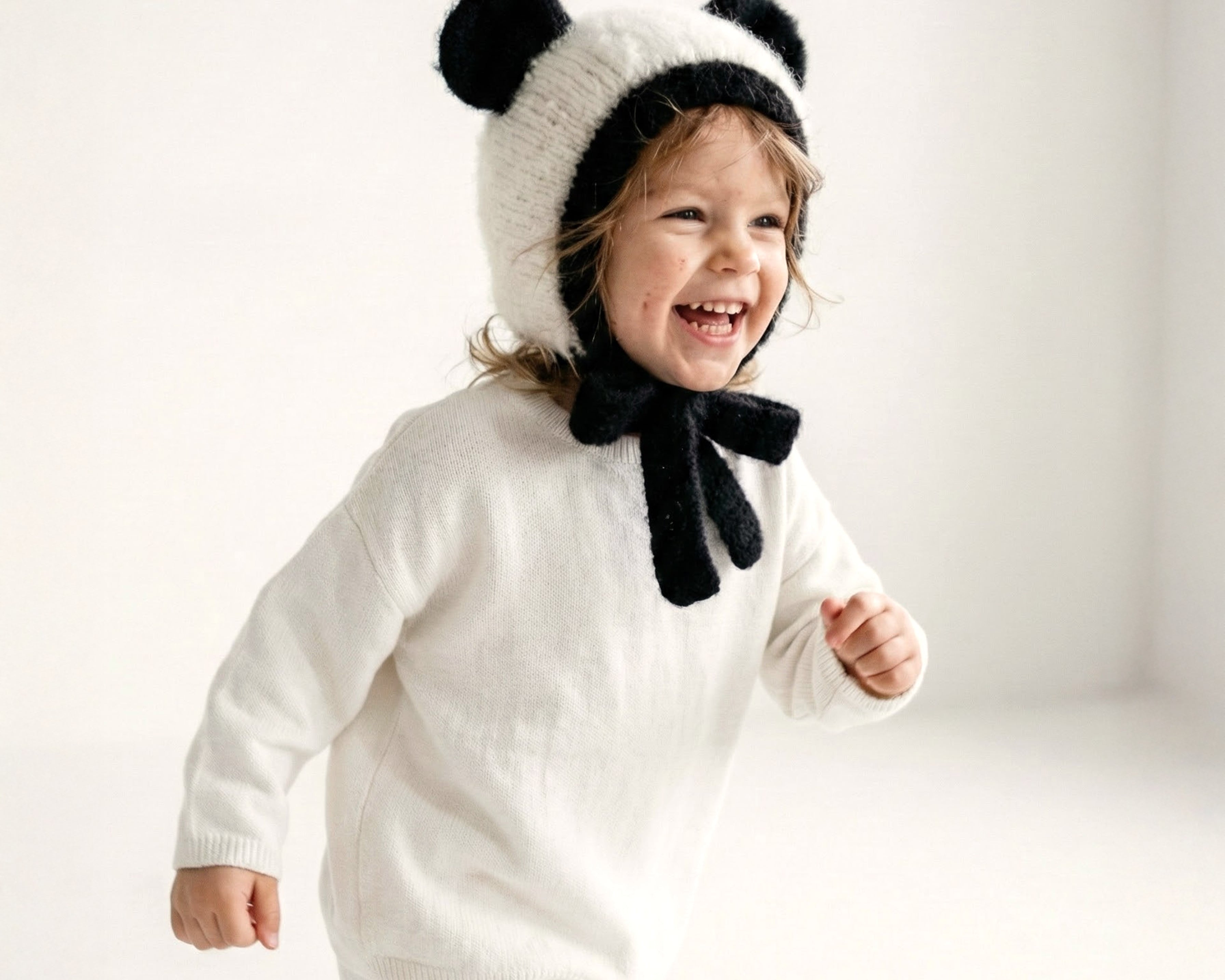A toddler wearing the Panda Bonnet, a hand knit alpaca kids hat from the Gang of Kids Autumn/Winter 2026 collection.