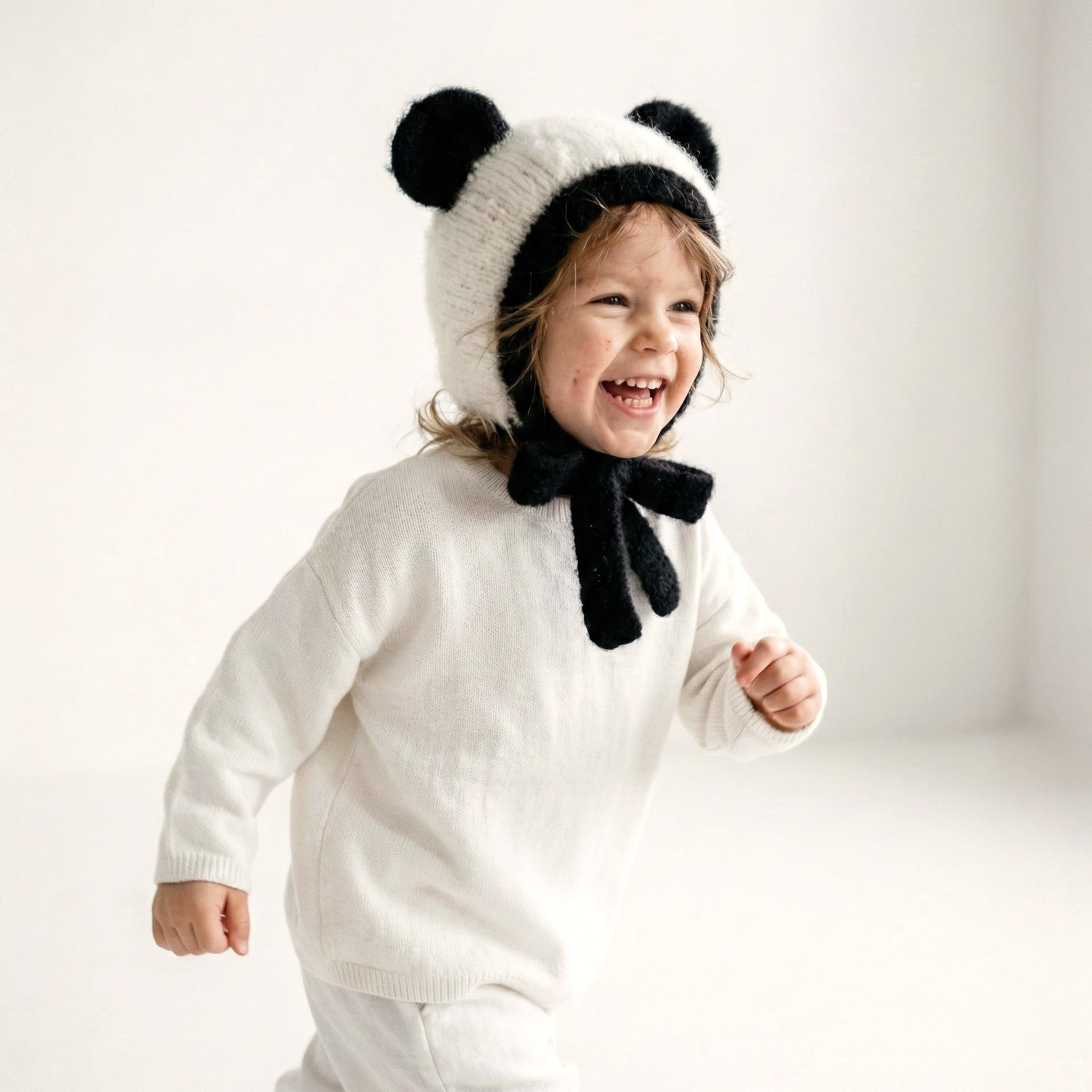 A toddler wearing the Panda Bonnet, a hand knit alpaca kids hat from the Gang of Kids Autumn/Winter 2026 collection.