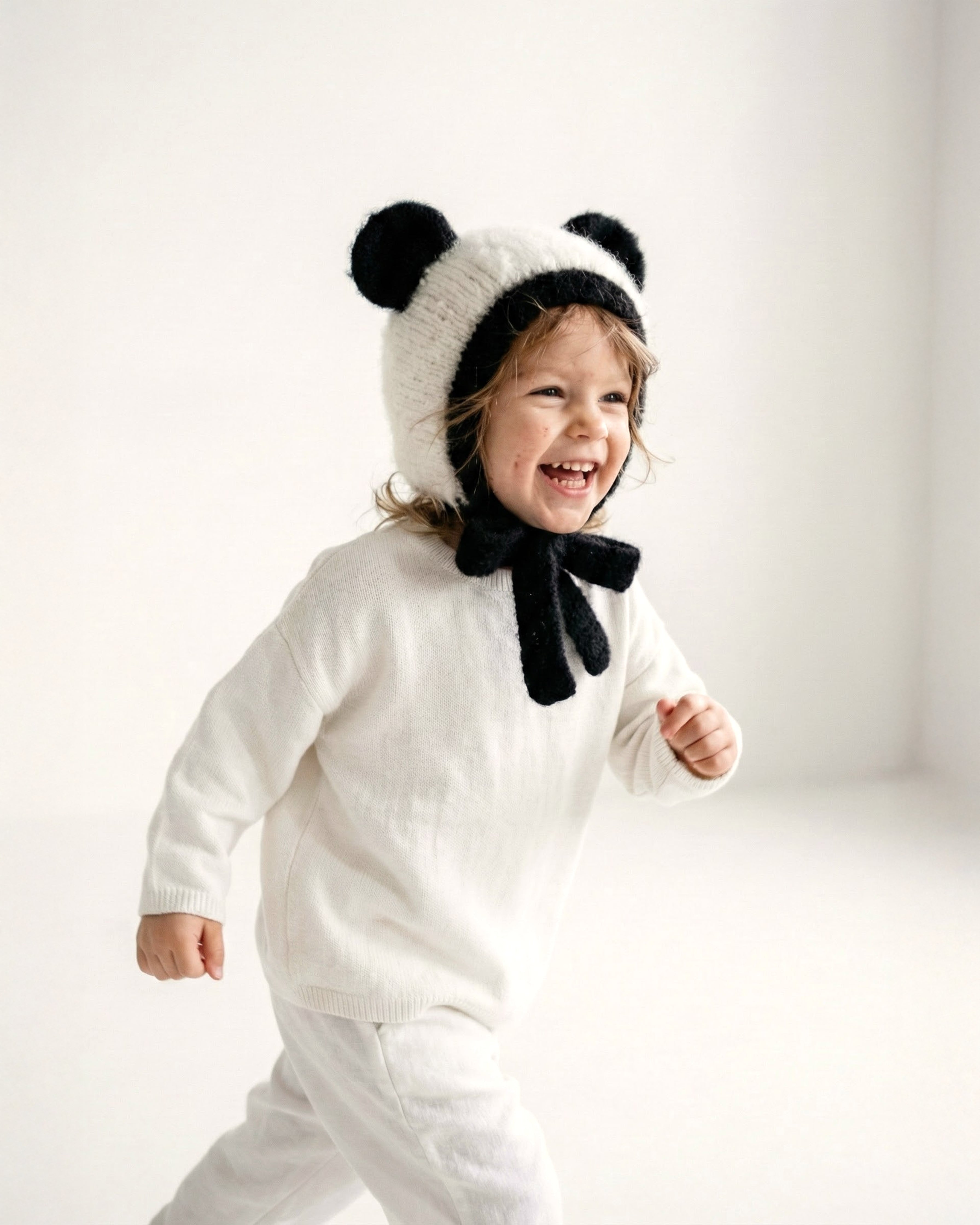 A toddler wearing the Panda Bonnet, a hand knit alpaca kids hat from the Gang of Kids Autumn/Winter 2026 collection.