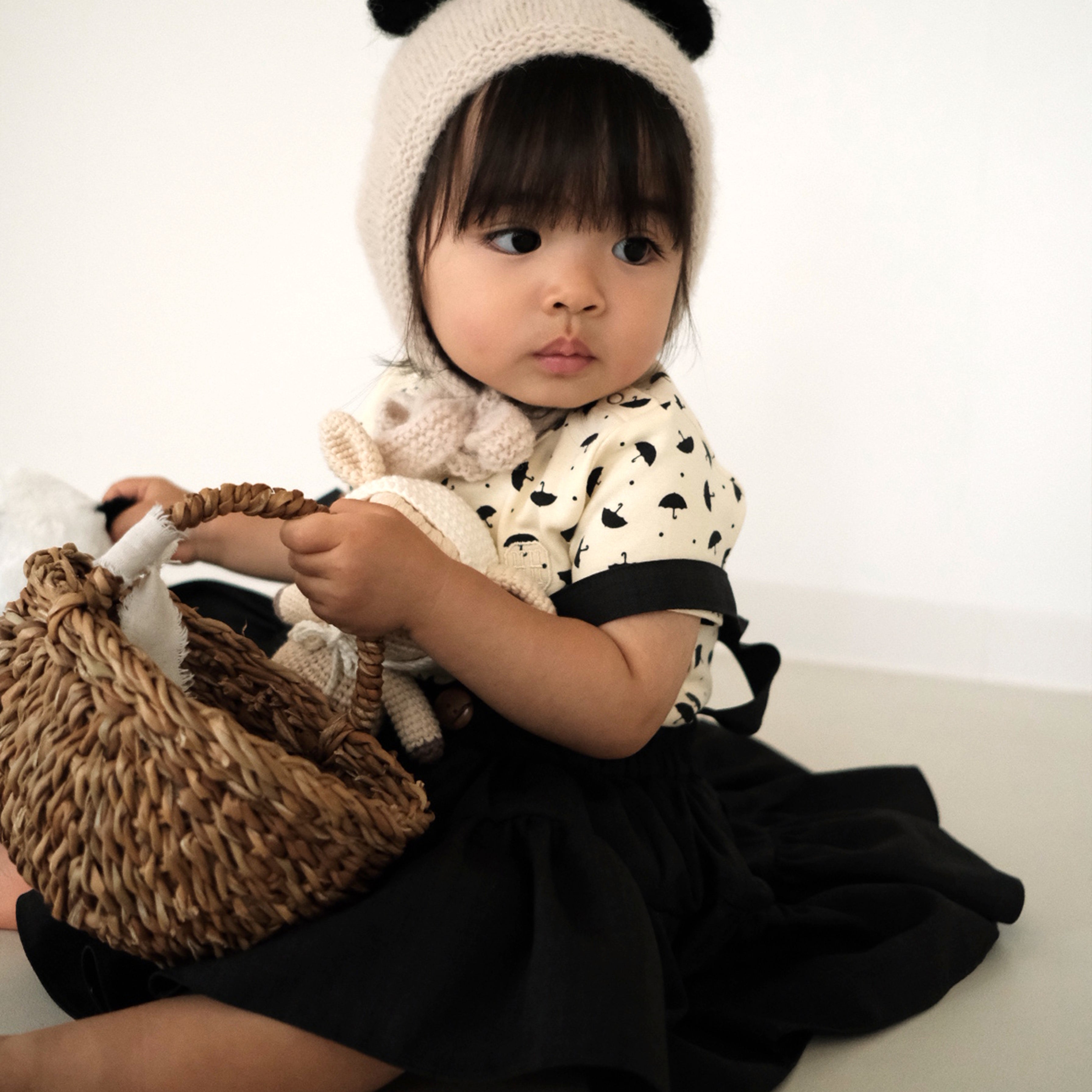 A toddler girl wearing the Panda Bonnet, a hand knit baby alpaca hat, from the Gang of Kids Autumn/Winter 2026 collection.