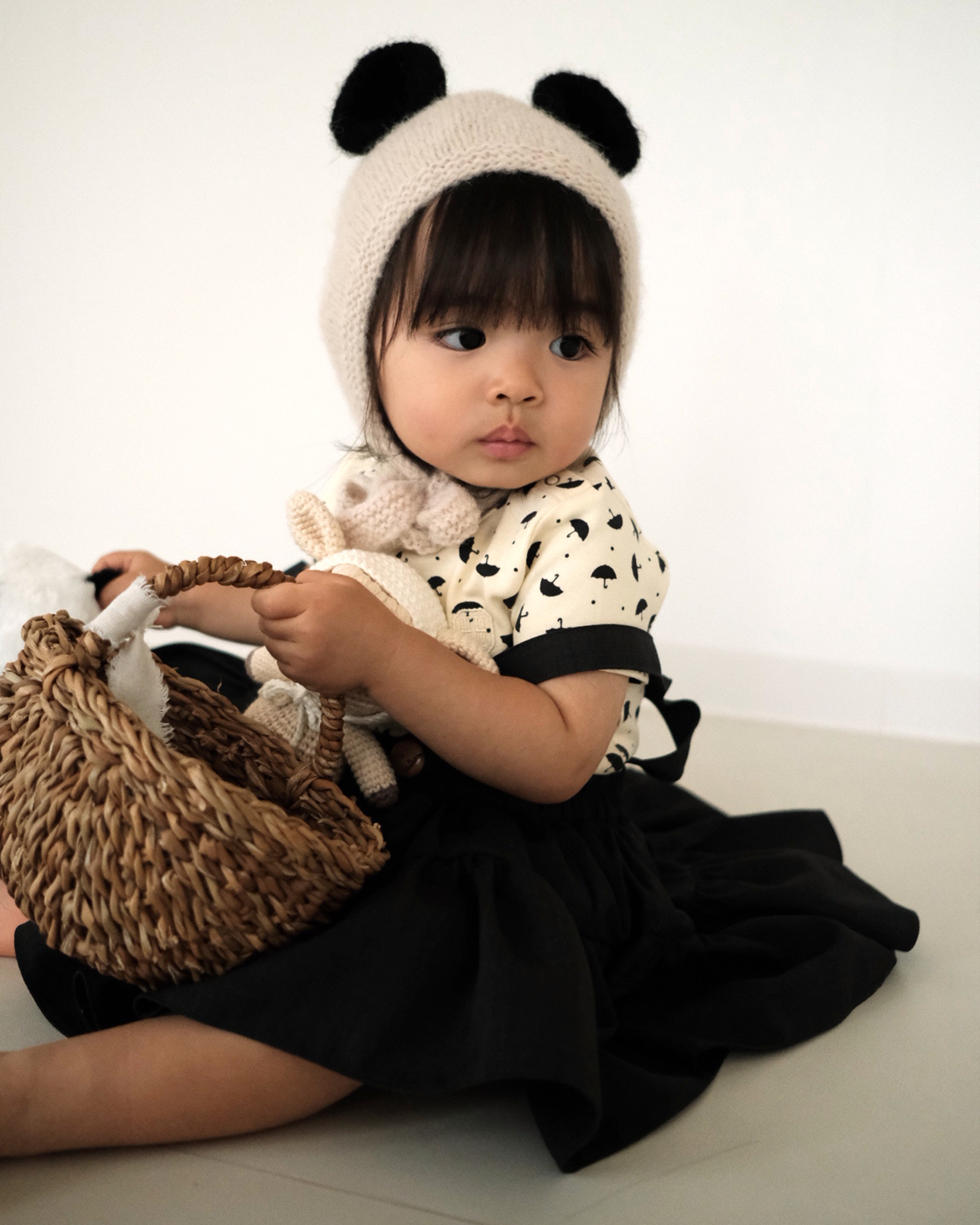 A toddler girl wearing the Panda Bonnet, a hand knit baby alpaca hat, from the Gang of Kids Autumn/Winter 2026 collection.