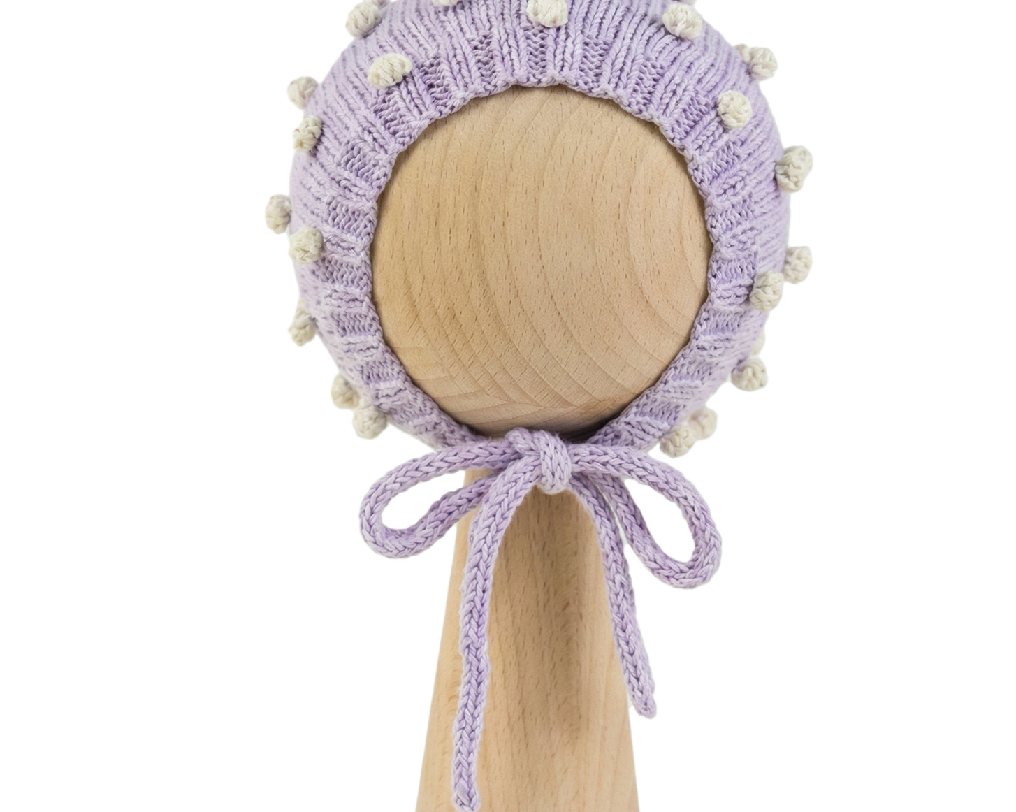 Hand-knitted lavender organic cotton baby bonnet with white popcorn texture on a wooden stand