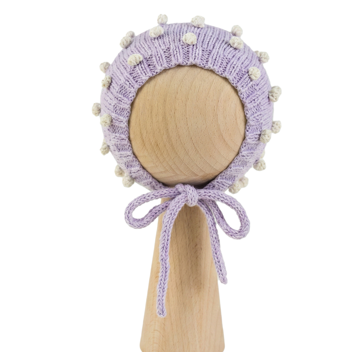 Hand-knitted lavender organic cotton baby bonnet with white popcorn texture on a wooden stand