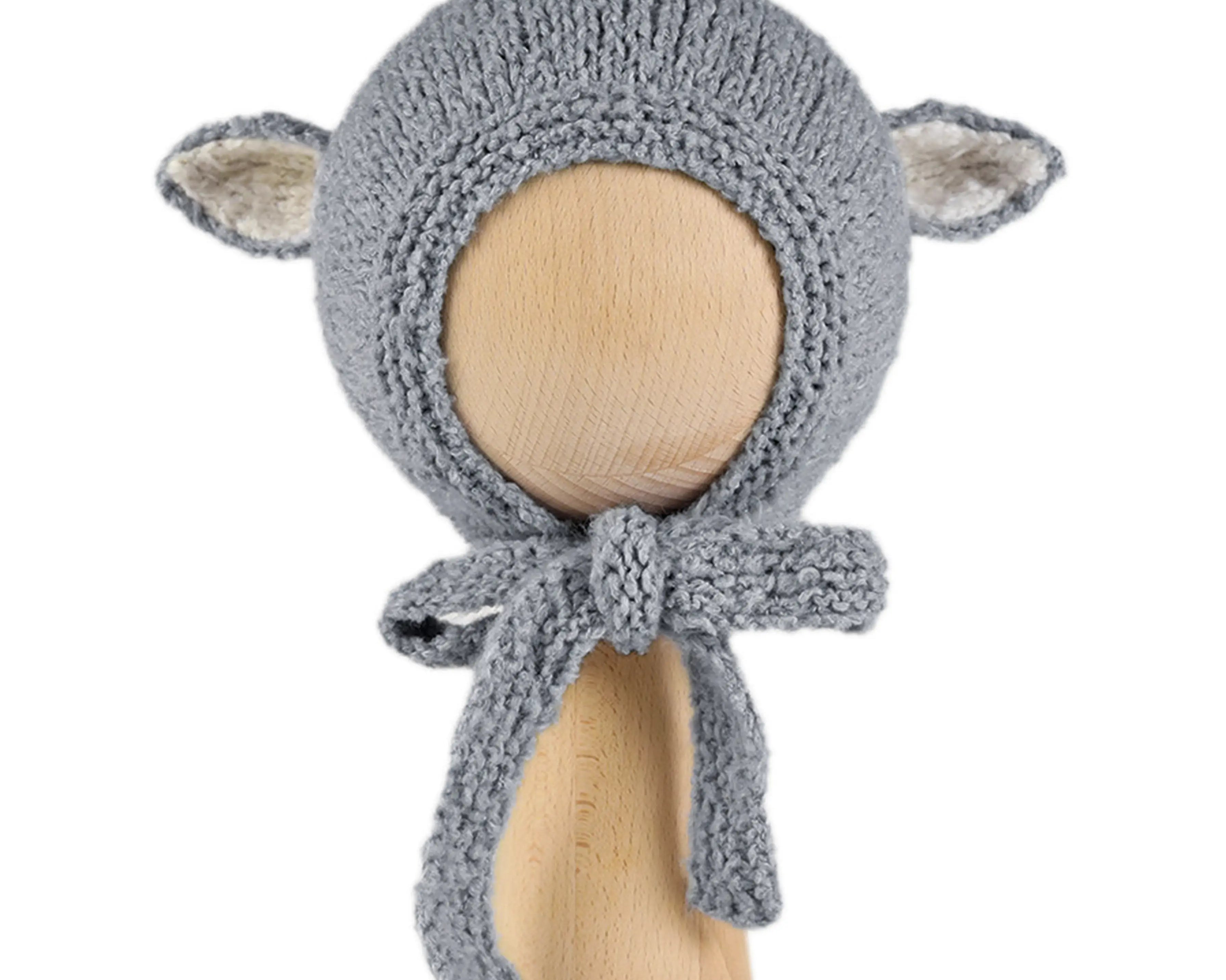 Sheep Bonnet in Charcoal, a knitted cotton bonnet with ecru-lined ears and knitted ties, shown on a wooden display head.
